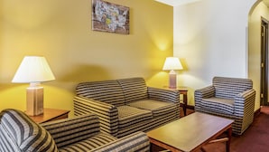 A hotel room with striped sofas, a wooden coffee table, two lamps, and a wall art piece. - Econo Lodge Inn and Suites Albuquerque East I-40 Eubank Exit (Albuquerque)
