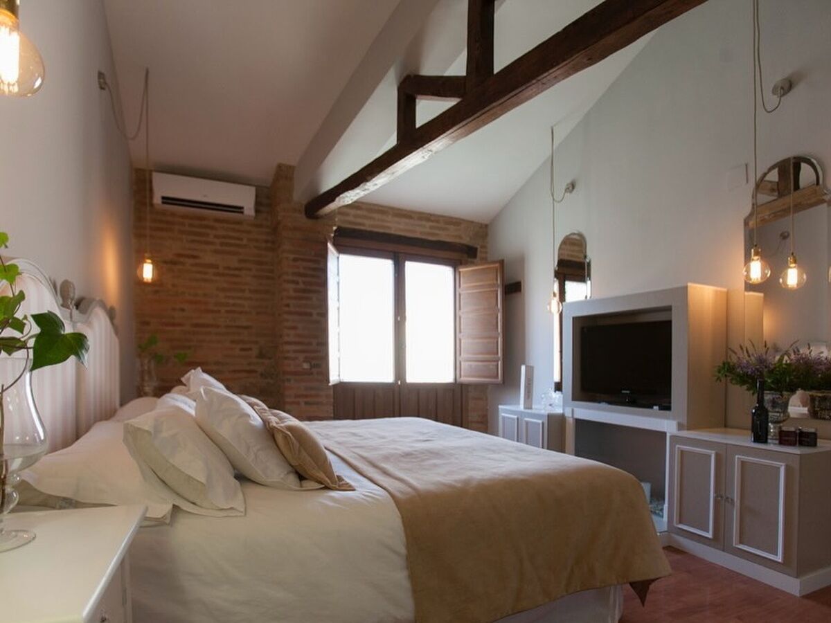 Ein Schlafzimmer mit einem großen Bett, einem Fernseher, einer Backsteinwand und einem Fenster.