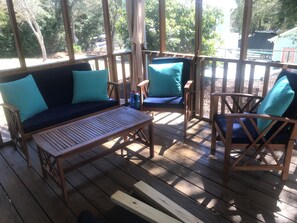 Una terraza de madera con un sofá, sillas y una mesa.