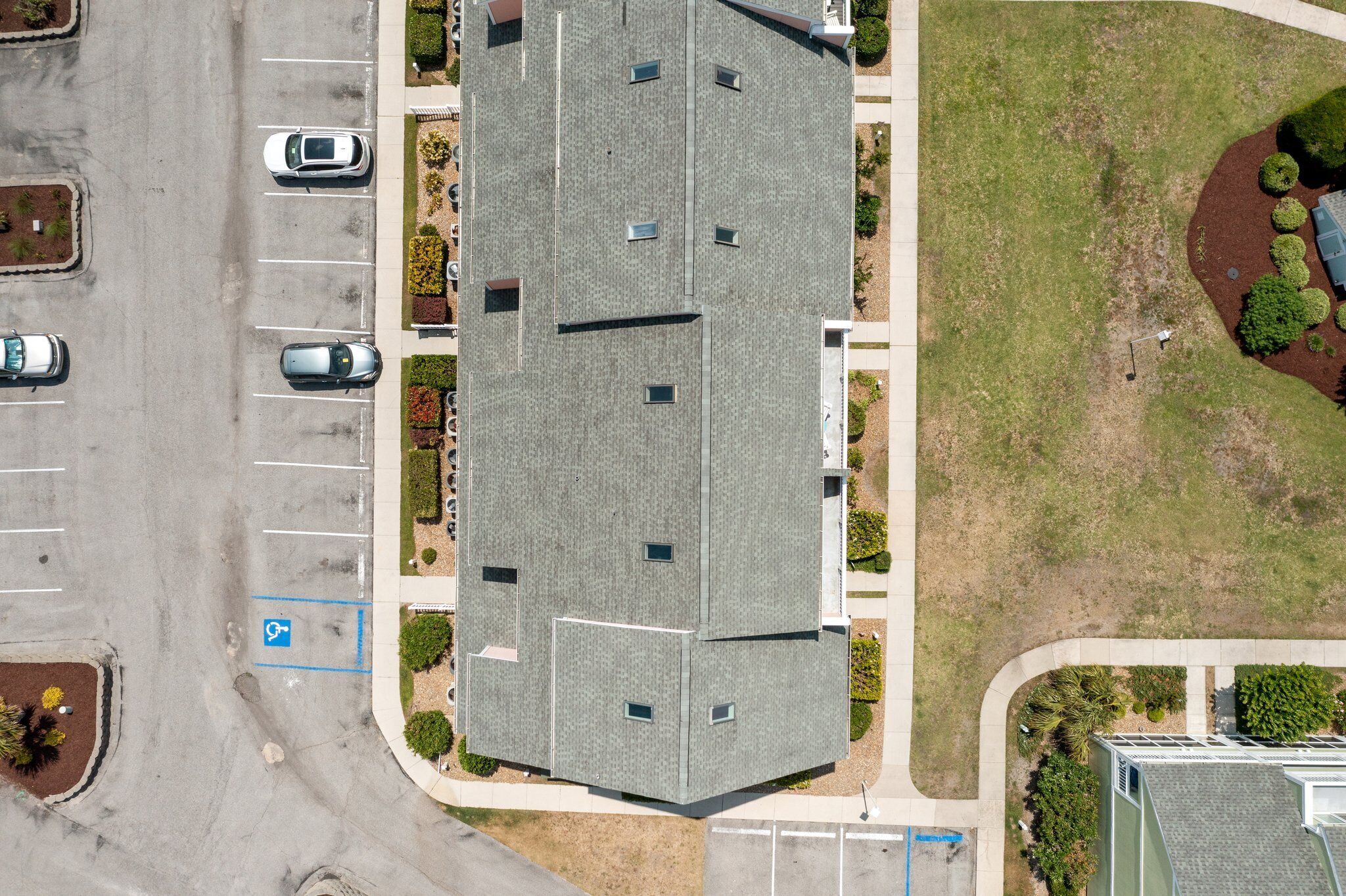 Un immeuble à plusieurs étages, doté d’un toit plat, d’un parking et d’espaces verts aménagés.
