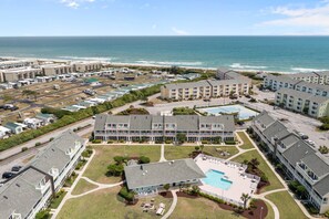 A coastal hotel with multiple buildings, a swimming pool, and a view of the ocean. - Studio Getaway with Balcony & Pool in Pebble Beach (Emerald Isle)