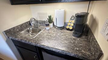 Une cuisine dotée d’un plan de travail en granit, d’un évier en acier inoxydable, d’une machine à café et d’un lave-vaisselle.