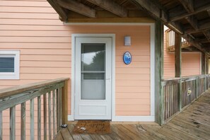 A wooden deck leading to a house with a white door and a mailbox. - Welcome to Sound of the Sea 102N (Emerald Isle)