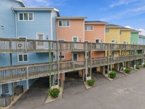 A multi-story building with a wooden deck connecting the floors. - Welcome to Sound of the Sea 102N (Emerald Isle)