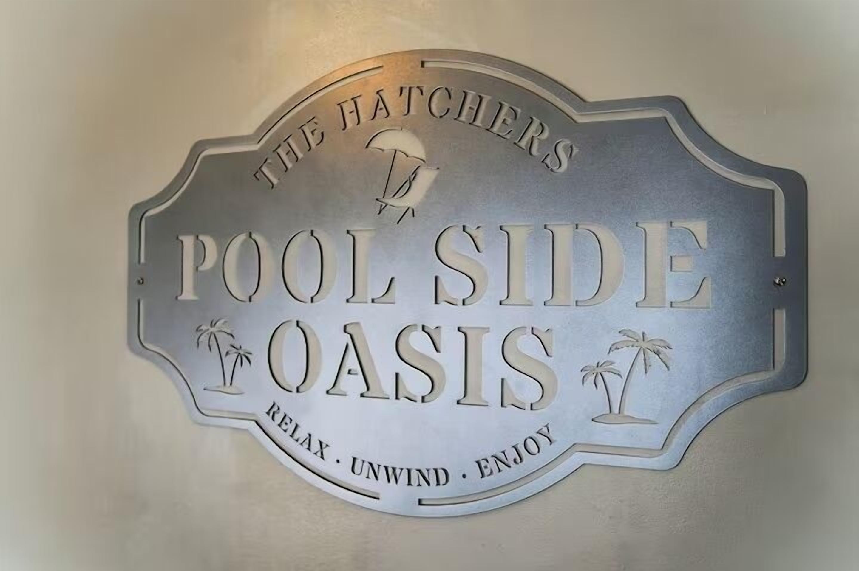 Une pancarte avec les inscriptions « The Hatchers Pool Side Oasis » et « Détendez-vous. Reposez-vous. Profitez-en. »