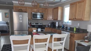 A modern kitchen with wooden cabinets, stainless steel appliances, and a dining area with white chairs.