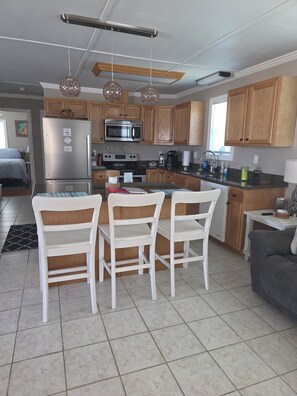 A modern kitchen with wooden cabinets, stainless steel appliances, and a dining area with white chairs.