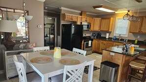 A kitchen with wooden cabinets, a black refrigerator, a microwave, and a sink.