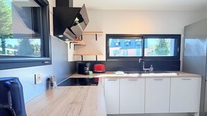 Una cocina moderna con encimera de madera, armarios blancos, estufa integrada y ventana con vistas a un barrio residencial.