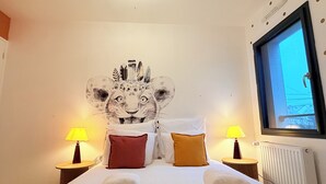 Una habitación de hotel con una cama, dos lámparas de noche, un televisor montado en la pared y un radiador.