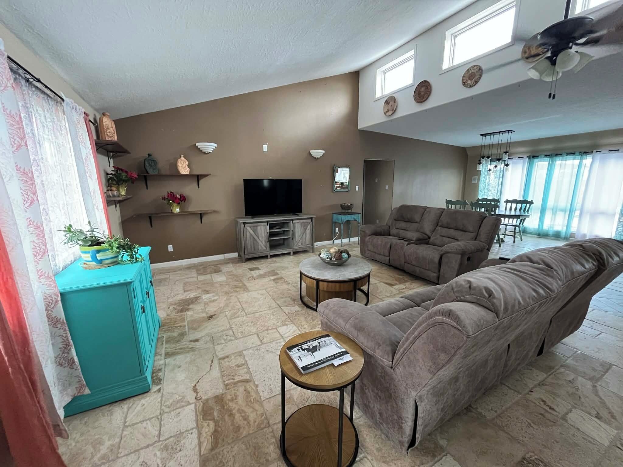 A living room with a sofa, TV, and a dining area with chairs.