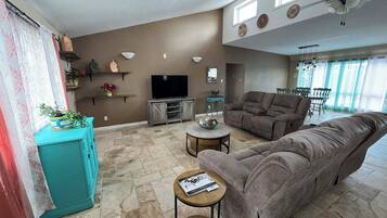 A living room with a sofa, TV, and a dining area with chairs.