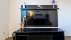 A black entertainment unit with a flat-screen TV, a small elephant figurine, and a giraffe figurine on the left.