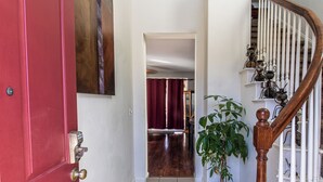 A staircase with a wooden handrail and white balusters, leading to a landing with a red door and a metal door lock.