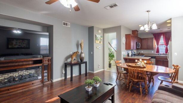 A living room with a fireplace, a dining area with wooden furniture, and a kitchen with modern appliances.