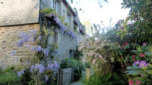 Un bâtiment en pierre avec un étroit sentier menant à une porte en bois.