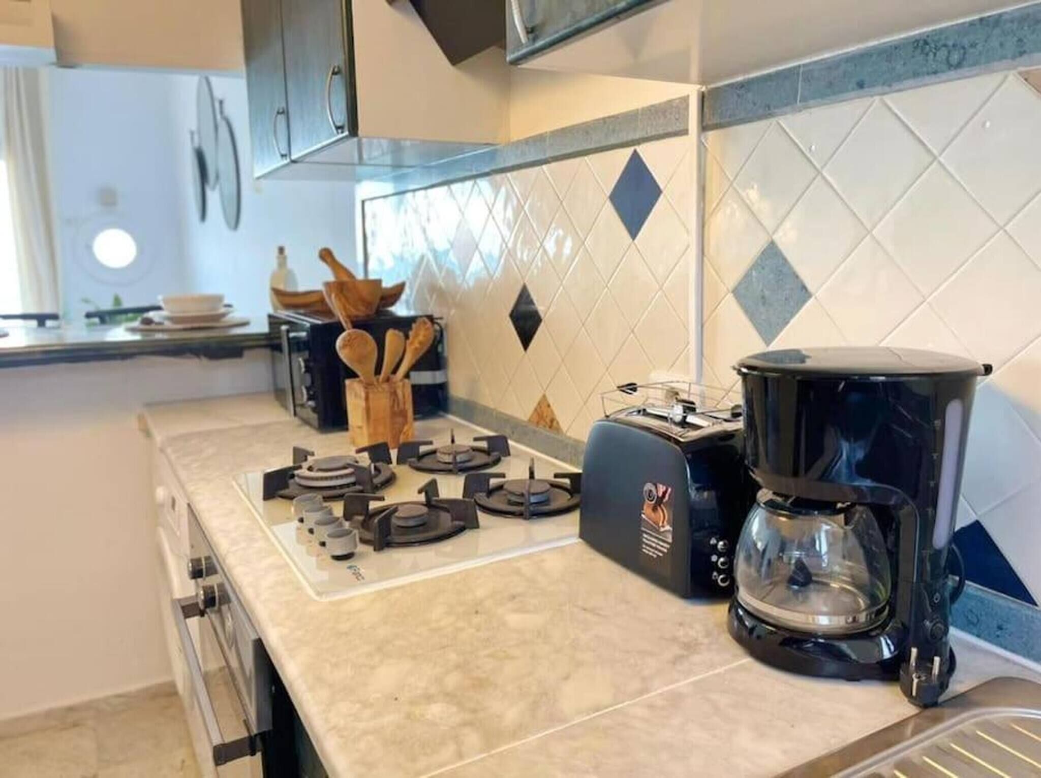 A kitchen with a gas stove, a coffee maker, and a toaster.