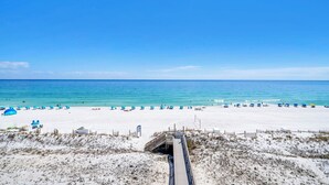 A beach with a wooden boardwalk leading to the water, beach chairs, and umbrellas. - ☀️Gulf Dunes 515 - Still Waters | Gulf Front Views | Beach Service☀️ (Fort Walton Beach)