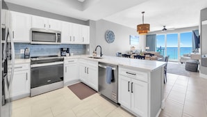 A modern kitchen with white cabinets, stainless steel appliances, and a large island. - ☀️Gulf Dunes 515 - Still Waters | Gulf Front Views | Beach Service☀️ (Fort Walton Beach)