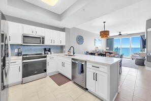 A modern kitchen with white cabinets, stainless steel appliances, and a large island. - ☀️Gulf Dunes 515 - Still Waters | Gulf Front Views | Beach Service☀️ (Fort Walton Beach)
