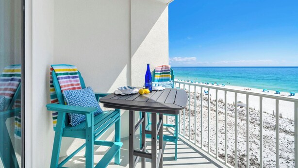 A balcony with turquoise chairs, a small table, and a view of the beach. - ☀️Gulf Dunes 515 - Still Waters | Gulf Front Views | Beach Service☀️ (Fort Walton Beach)