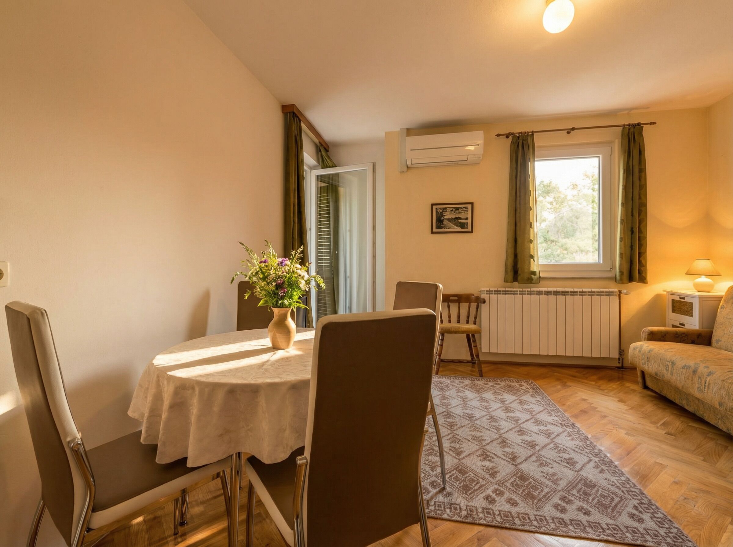 Un salon confortable avec une table à manger, des chaises, un canapé, un radiateur et une fenêtre avec des rideaux.