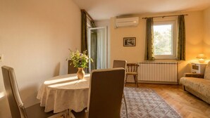 Un salon confortable avec une table à manger, des chaises, un canapé, un radiateur et une fenêtre avec des rideaux.