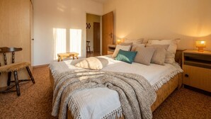 Une chambre à coucher avec un grand lit, des tables de chevet, une chaise en bois et une petite table.