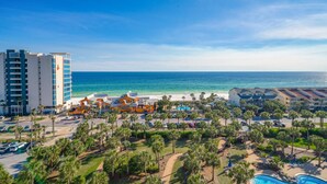 Un resort con vista a la playa, piscina y aparcamiento rodeado de palmeras.