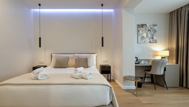 Et hotelværelse med seng, sengeborde, et skrivebord med stol og en lampe.