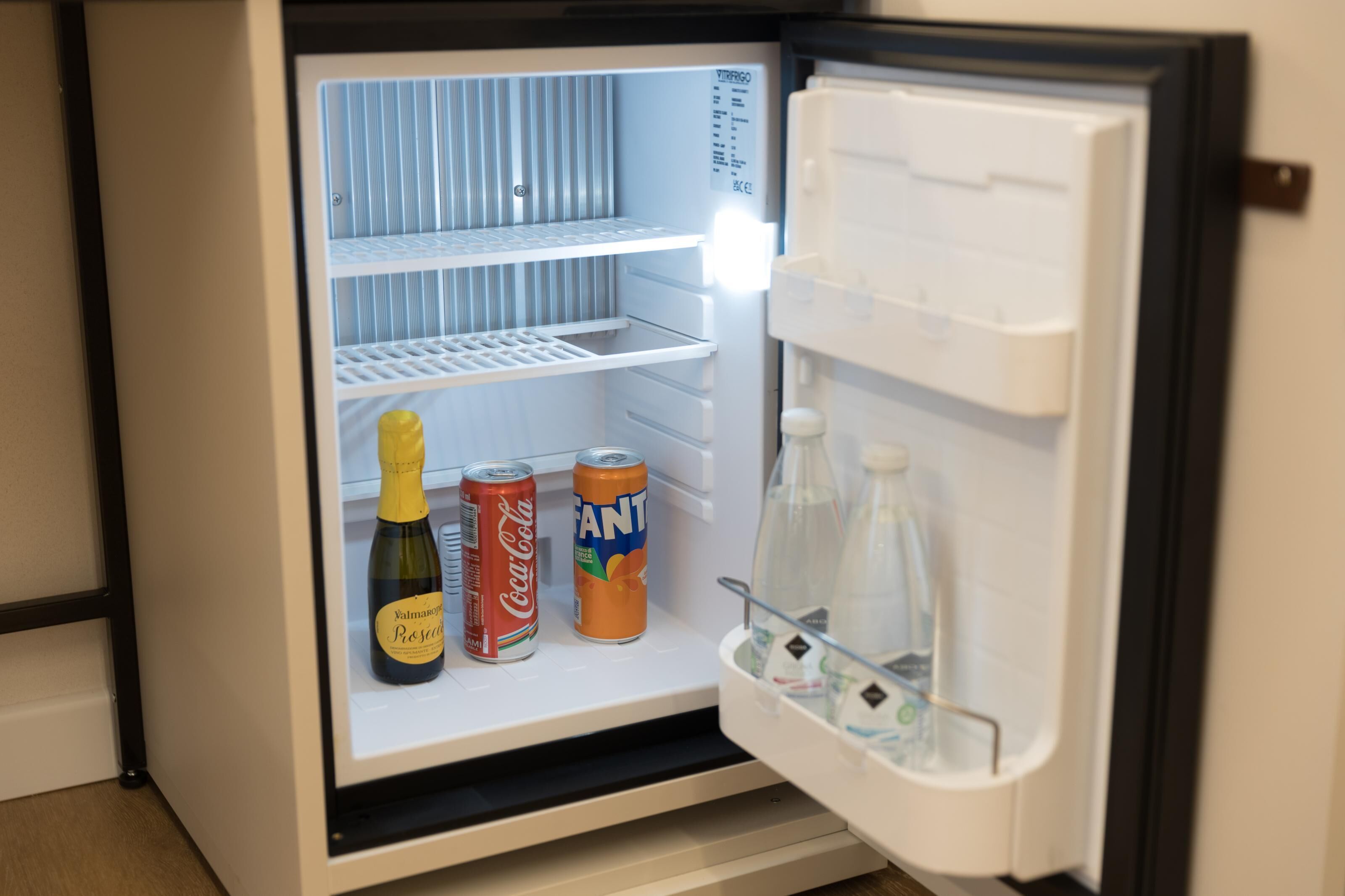 Ein offener Kühlschrank mit Regalen, einem Wasserspender und einem Gefrierfach.