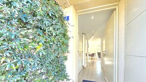 Un passadís amb una porta que marca 'LES ALLEES DE NOMENY' i condueix a una habitació amb una cadira i una taula.