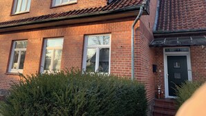 Un bâtiment à deux étages, construit en briques, avec un toit recouvert de tuiles, de nombreuses fenêtres et une porte bien visible.