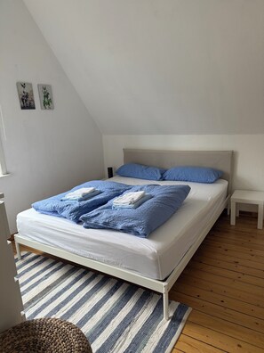 Une chambre à coucher avec un lit, une table de chevet, un tapis et un tableau accroché au mur.