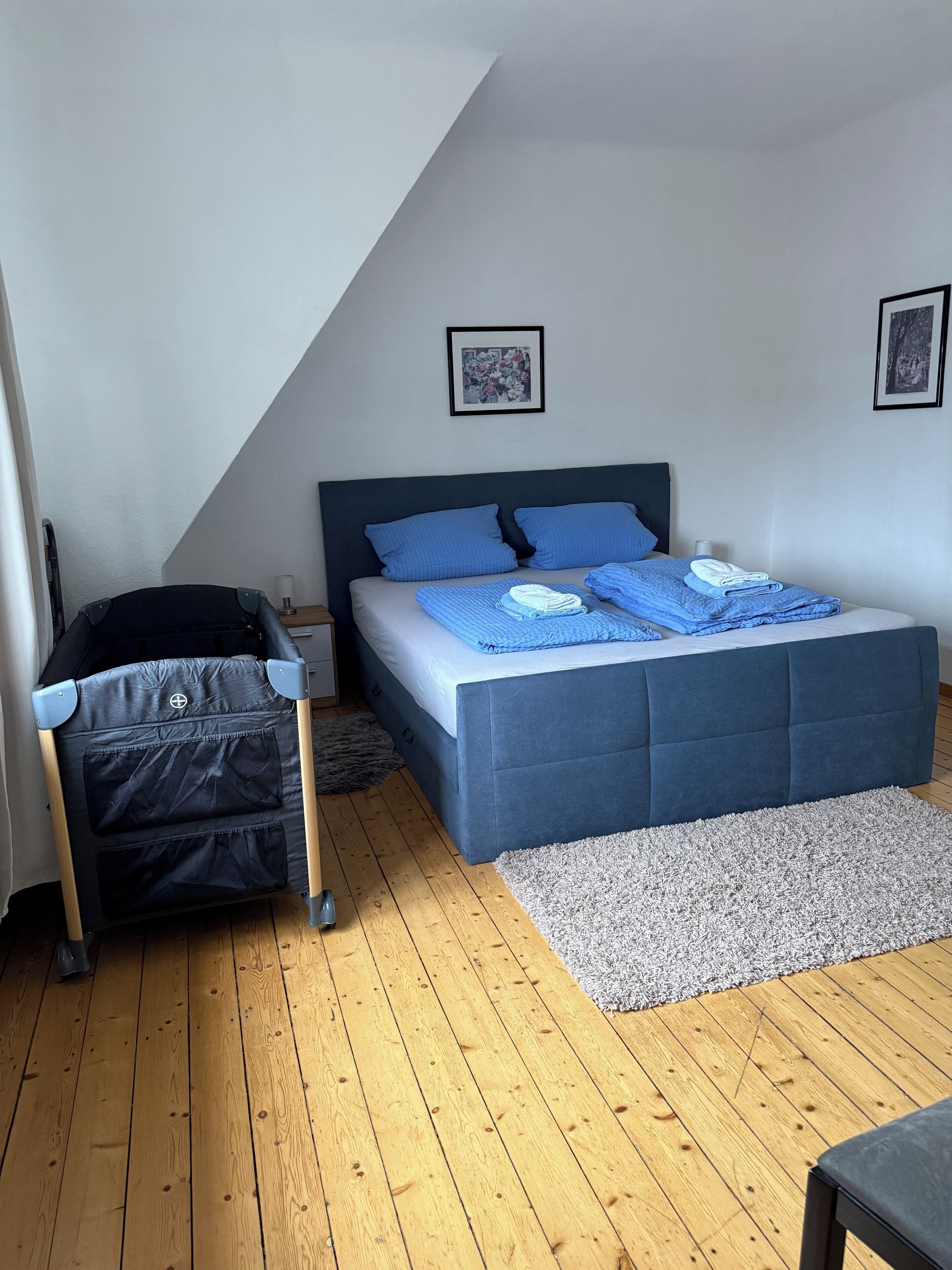 Une chambre à coucher avec un lit, une chaise, un tapis et deux tableaux encadrés accrochés au mur.