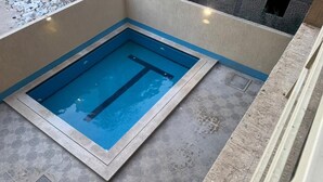 A small, rectangular pool with a blue interior, surrounded by a light-colored tiled floor and walls. - Two bedroom apartment with Swimming Pool in the Intercontinental area, Hurghada (Red Sea Governorate)