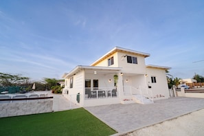 A two-story house with a balcony, a small porch, and a paved driveway.