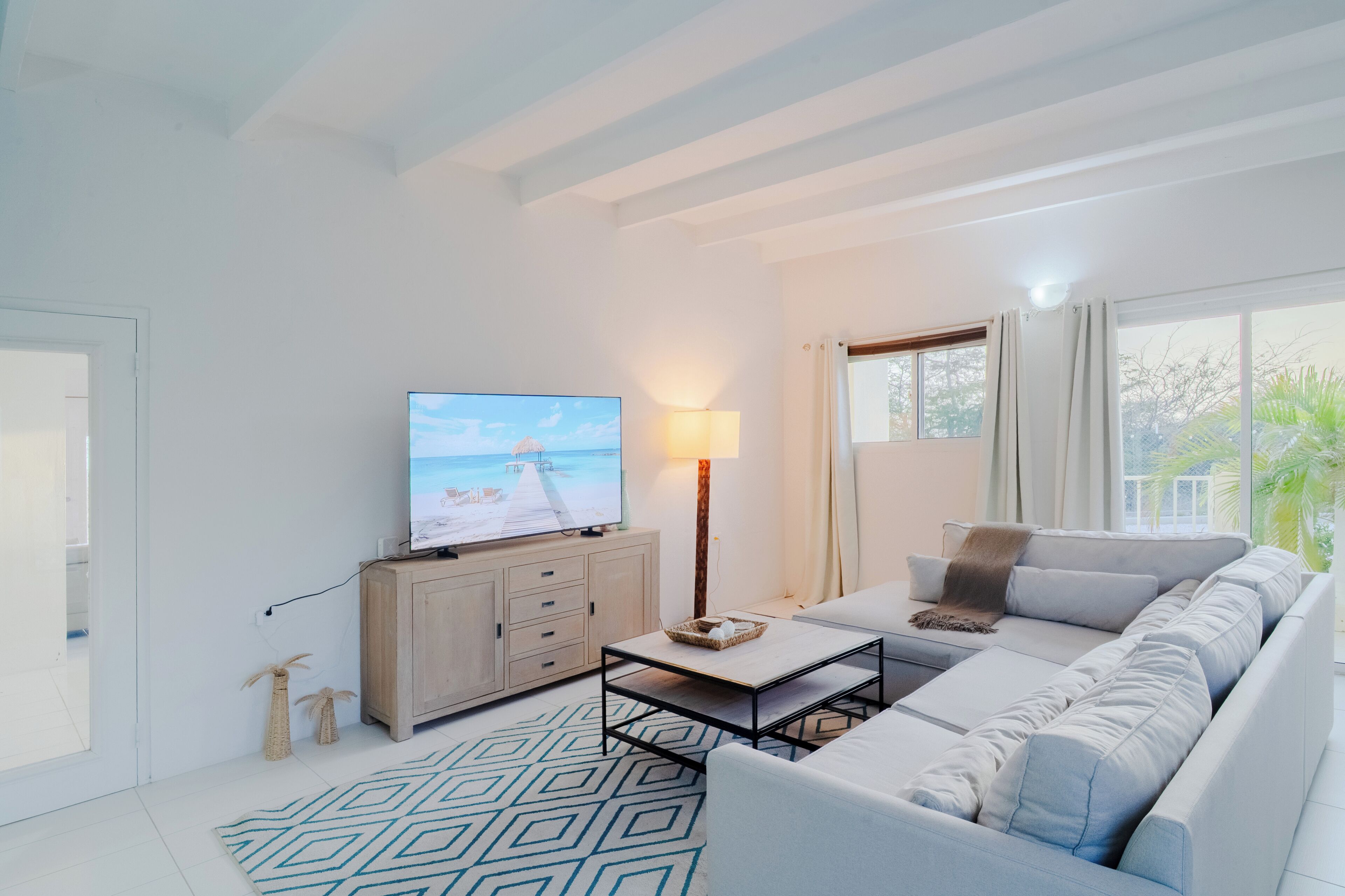A modern living room with a television, sofa, coffee table, and a patterned rug.