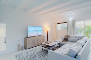 A modern living room with a television, sofa, coffee table, and a patterned rug. - Villa on a Hill | Private Pool, Ocean Views, Aruba (Savaneta)