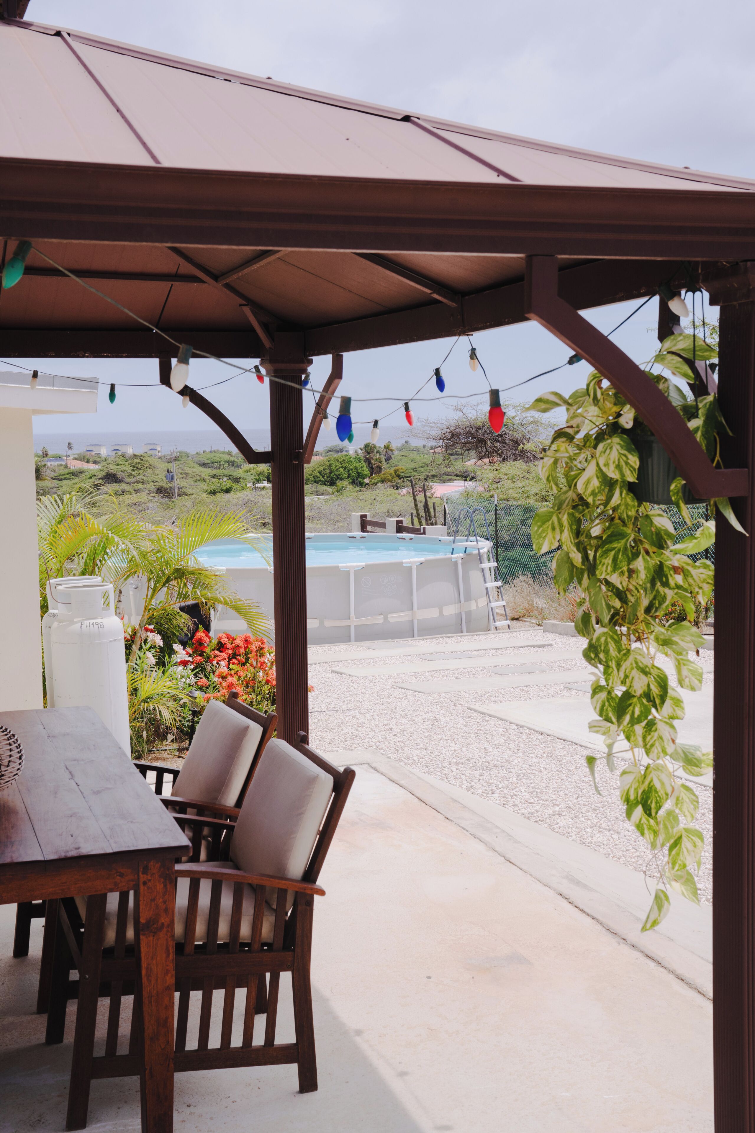 A covered patio area with a pool, outdoor seating, and a view of the landscape.