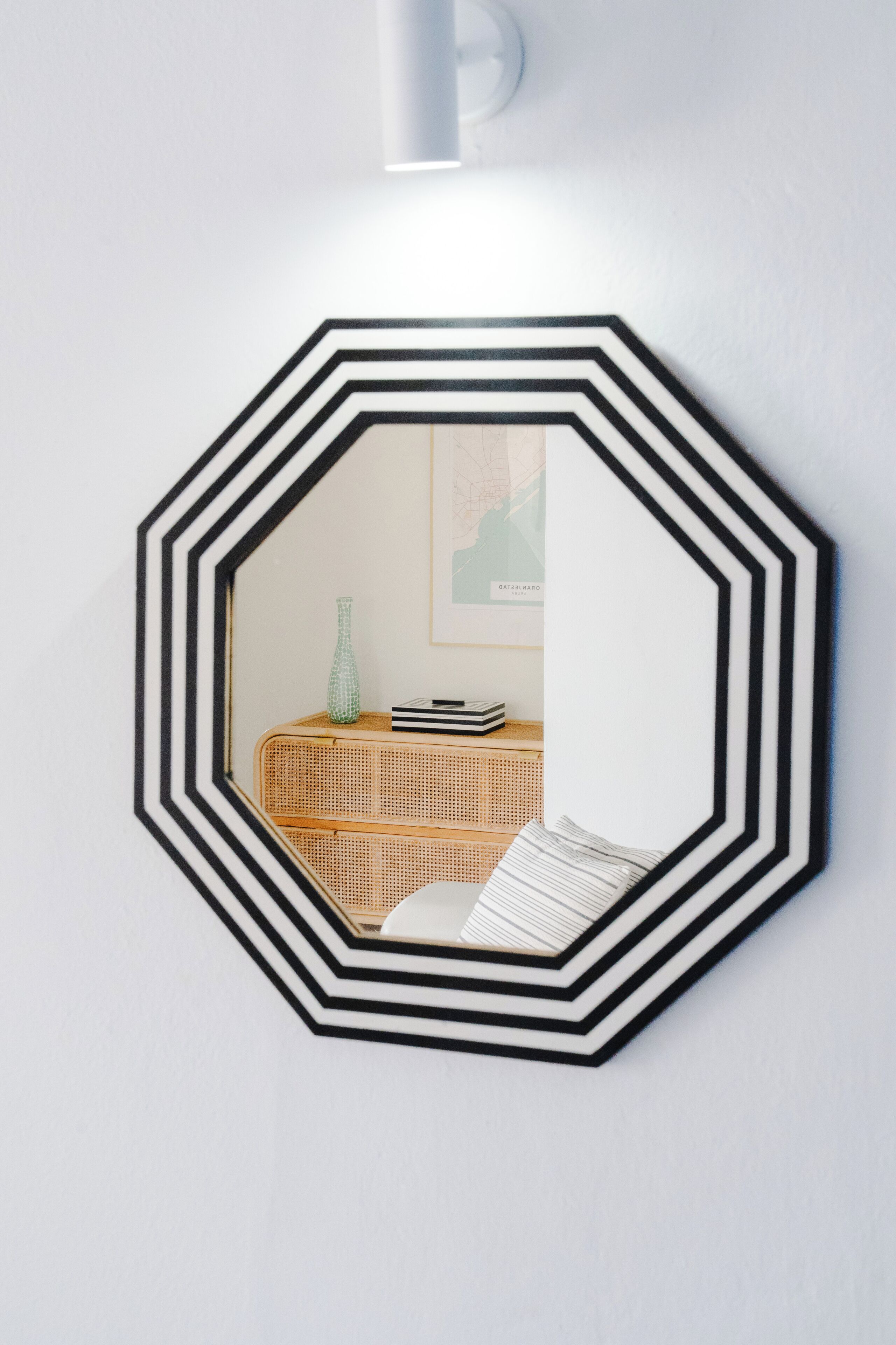 Ein wandmontierter, achteckiger Spiegel mit einem schwarz-weißen geometrischen Muster.