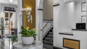 A modern interior with a marble column, a potted plant, a staircase, and a wall with geometric patterns. - 2br Deluxe w/ Balcony in Historic Hotel San Diego (San Diego)