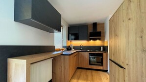 Une cuisine moderne avec des meubles en bois, un four encastré et une hotte noire.