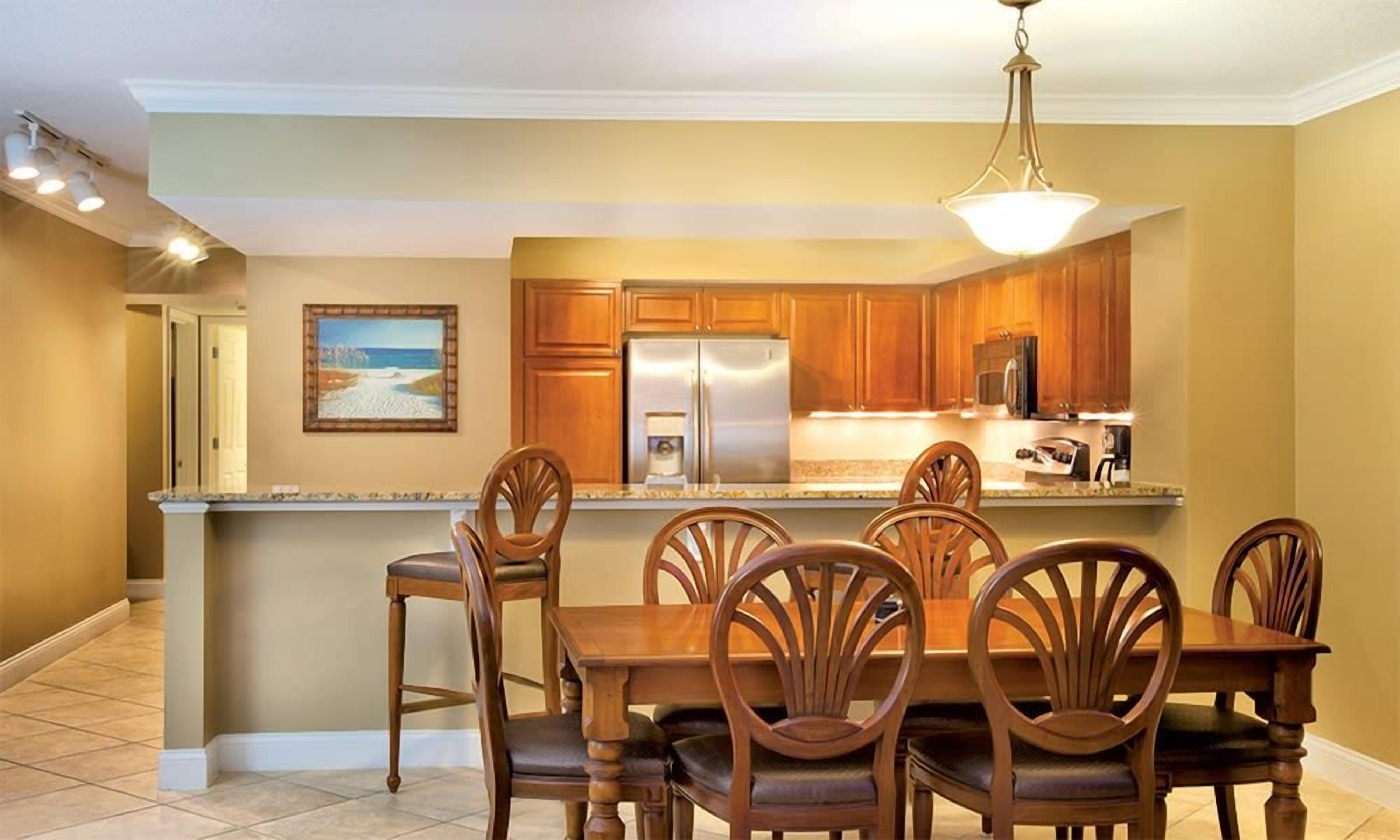 Una cocina con armarios de madera, un refrigerador de acero inoxidable y una zona de comedor con mesa y sillas.