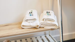 Twee netjes opgevouwen handdoeken met essentiële oliën op een houten plank in een hotelkamer.