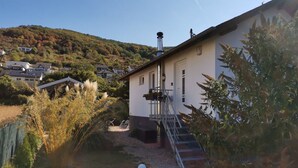 Una casa con un camino, un piccolo giardino e una collina sullo sfondo.
