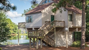 Une maison à deux étages avec une terrasse, un escalier et une vue sur un lac.