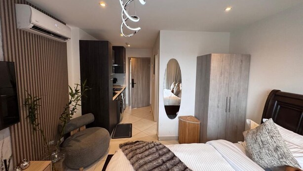 Une chambre à coucher moderne avec un lit, une table de chevet et un grand miroir.