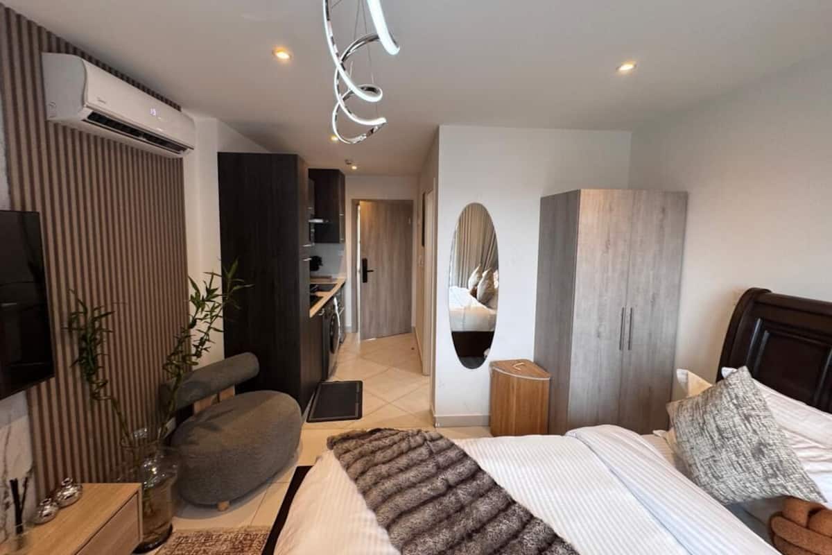 Un dormitorio moderno con cama, mesita de noche y un espejo grande.