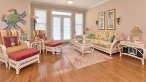 A living room with a sofa, chairs, a coffee table, and a decorative crab wall art. - Experience Oak Island living in "A Gift From Heaven," a 3BR water view retreat for 6. (Oak Island)